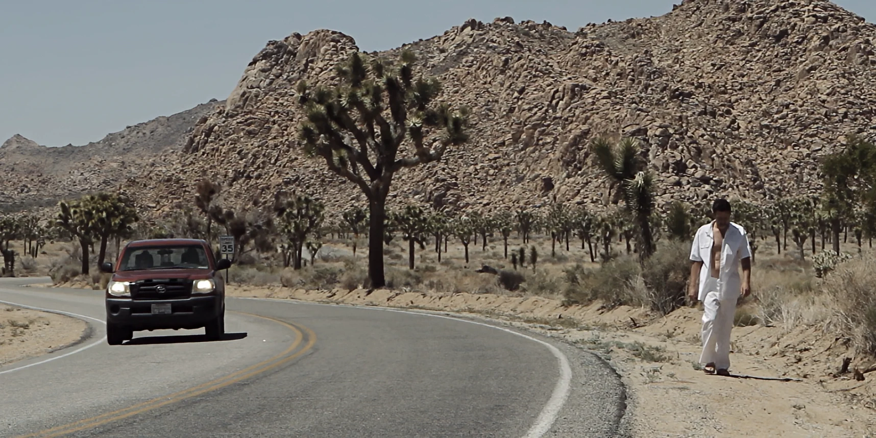 Man in white walking along a road bordering Joshua Tree desert in 88 short film