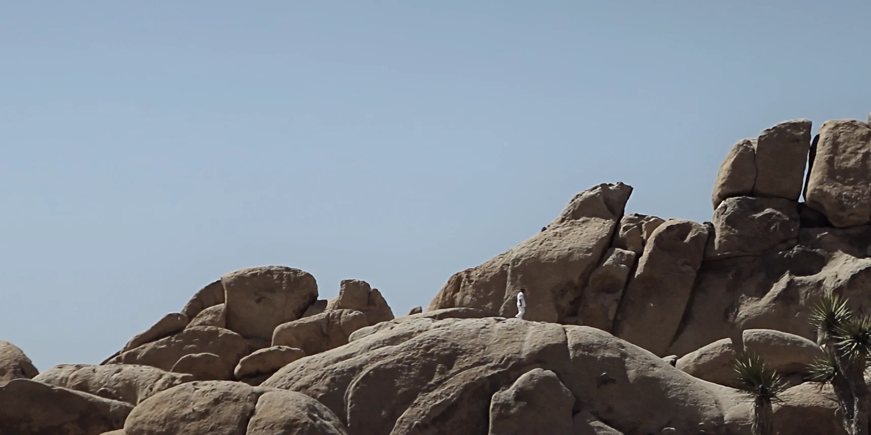 Tiny man walking on a huge magnificent rock in Joshua Tree desert, 88 short film