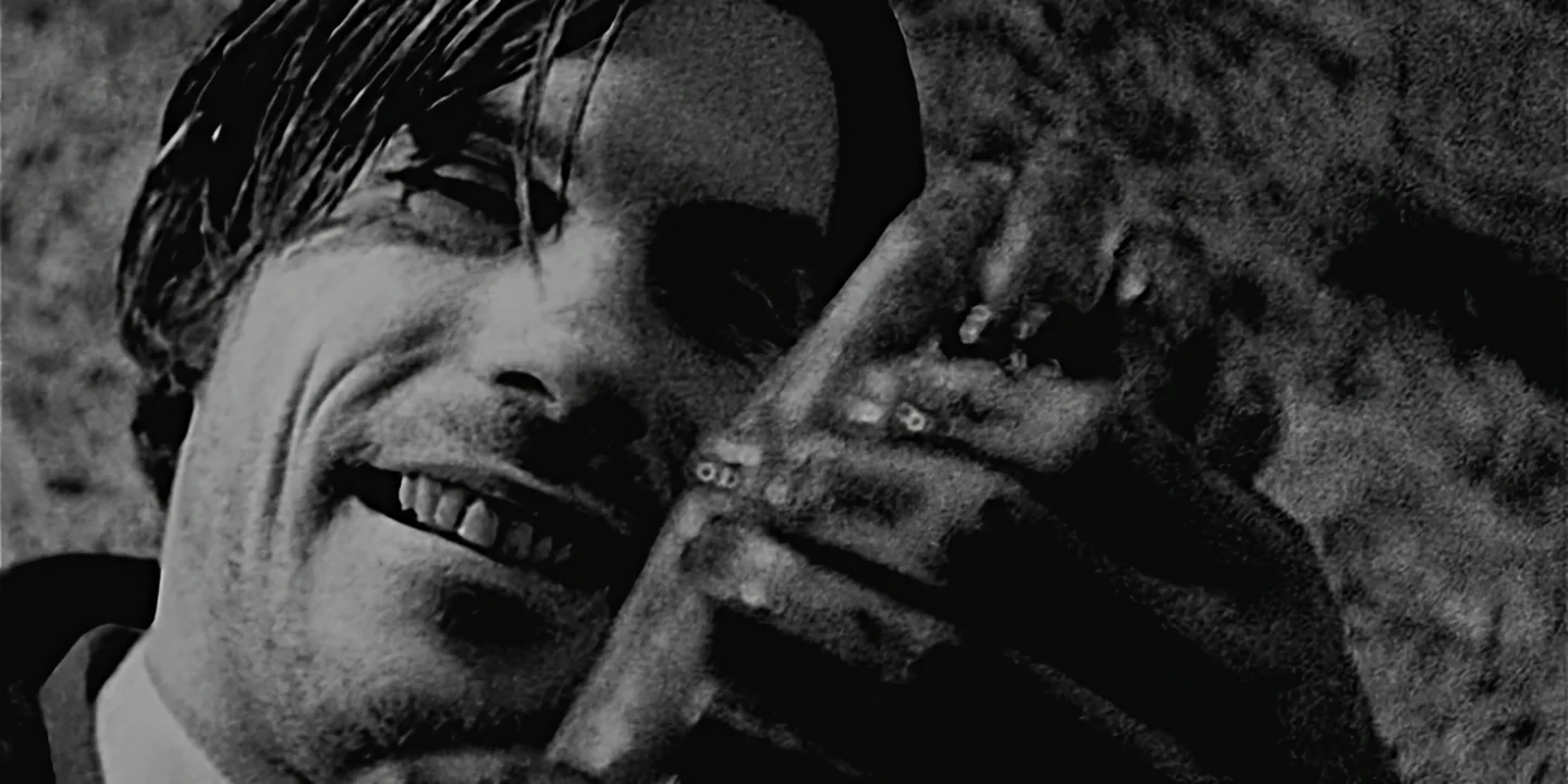 Close-up of young man smiling at bloody severed hand, crazy vibe like Un Chien Andalou, The Hand short film
