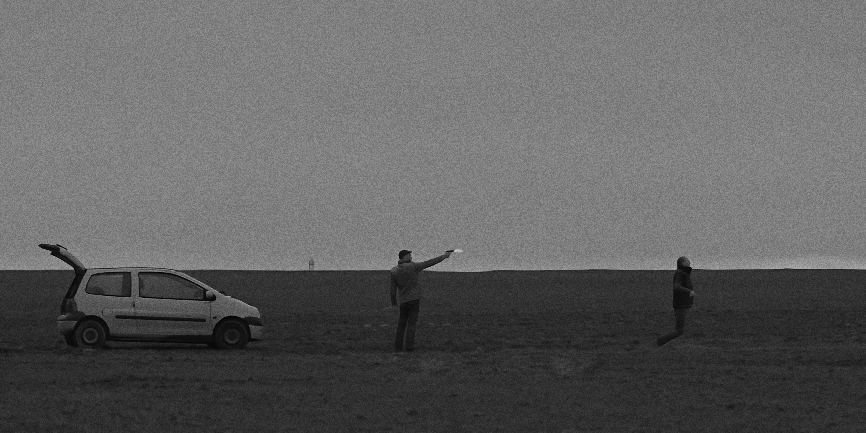Wide shot of sad deserted countryside, man executing another from behind in distance, black and white Twice as Far