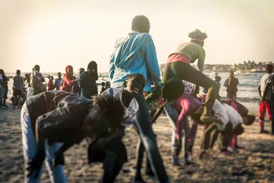 Children playing leapfrog on Ngor Village beach at sunset in Dakar, Senegal