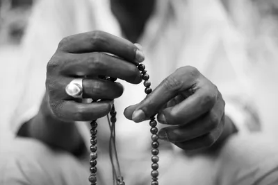 Extreme close-up black and white photo of a man's hands manipulating prayer beads in Dakar, Senegal