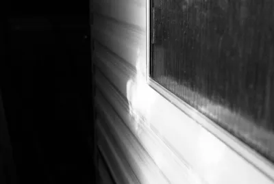 High-contrast black and white detail of a mobile home window under a cart shed, Brittany, France