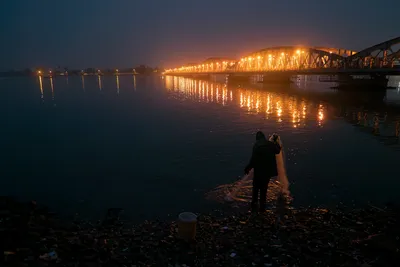 Fisherman pulling fishing net at night along Senegal River bank near Faidherbe Bridge in Saint-Louis, Senegal