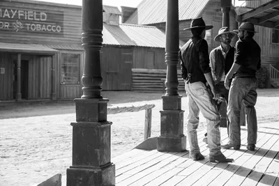 Black and white photo of three cowboys under a saloon porch in the Tabernas desert, Almería, Spain